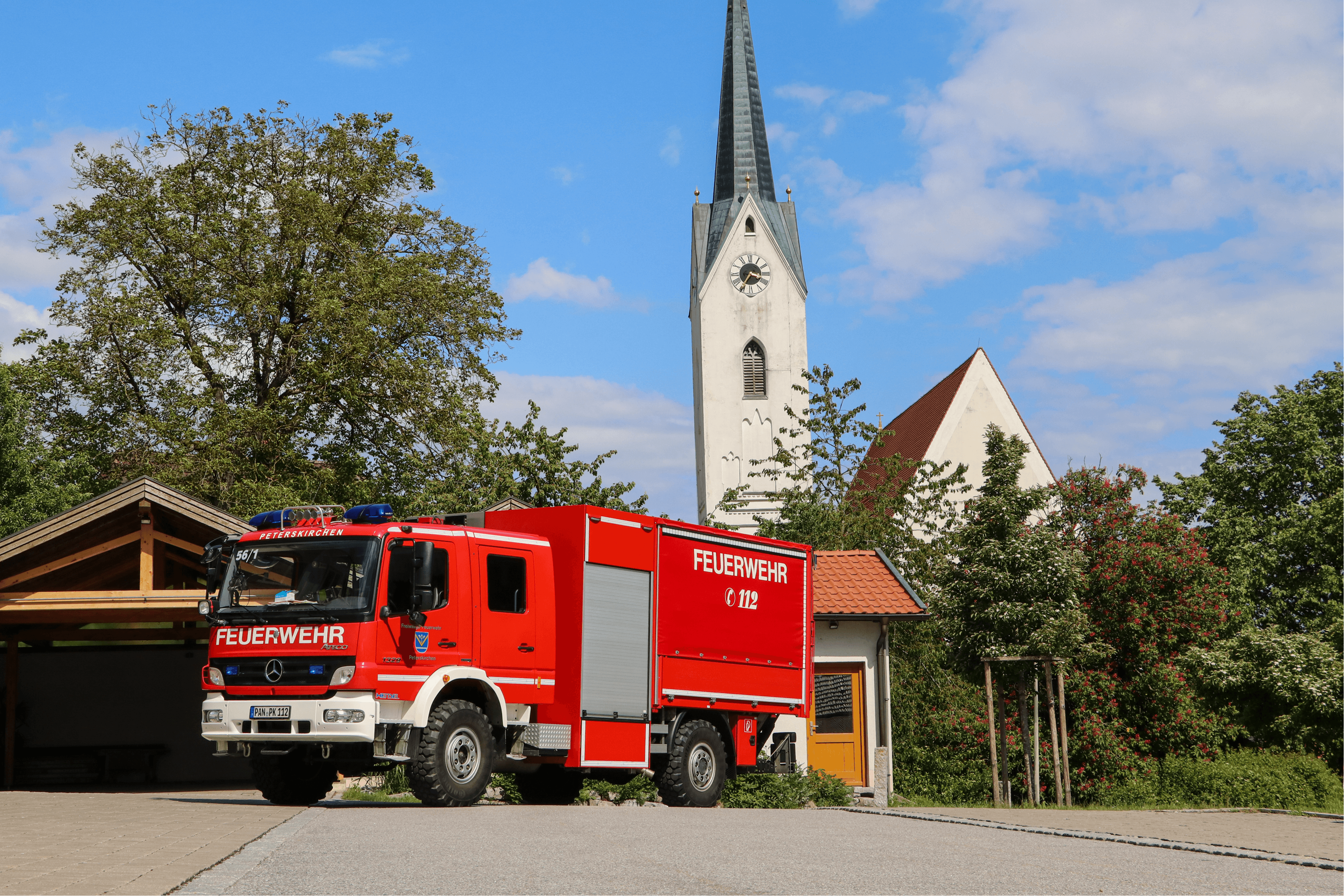 Gerätewagen Logistik (GW-L2) der Freiwilligen Feuerwehr Peterskirchen von vorne, im Hintergrund der Kirchturm von Peterskirchen